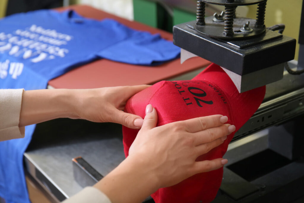 Young,Woman,Printing,On,Cap,At,Workshop