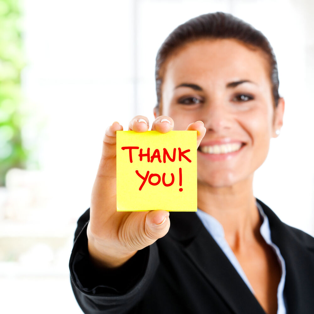 A woman holding a thank you note, saying thank you for your purhcase